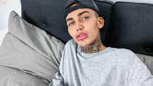 Tattooed Logan runs his hands over his slim torso, pushing up his grey sweatshirt to show his abs and chest, and slipping his other hand down the front of his black trousers.